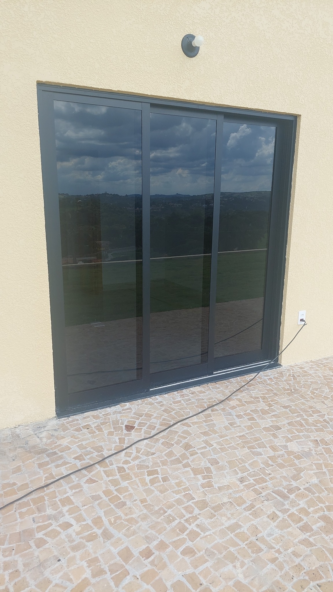 Porta de correr com três folhas em alumínio preto fosco e vidro fumê