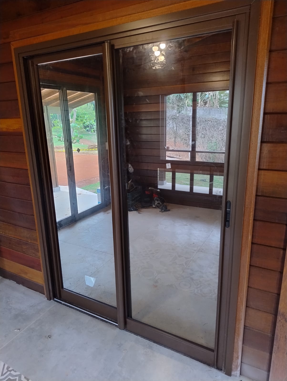 Porta de correr em alumínio marrom instalada em residência de madeira