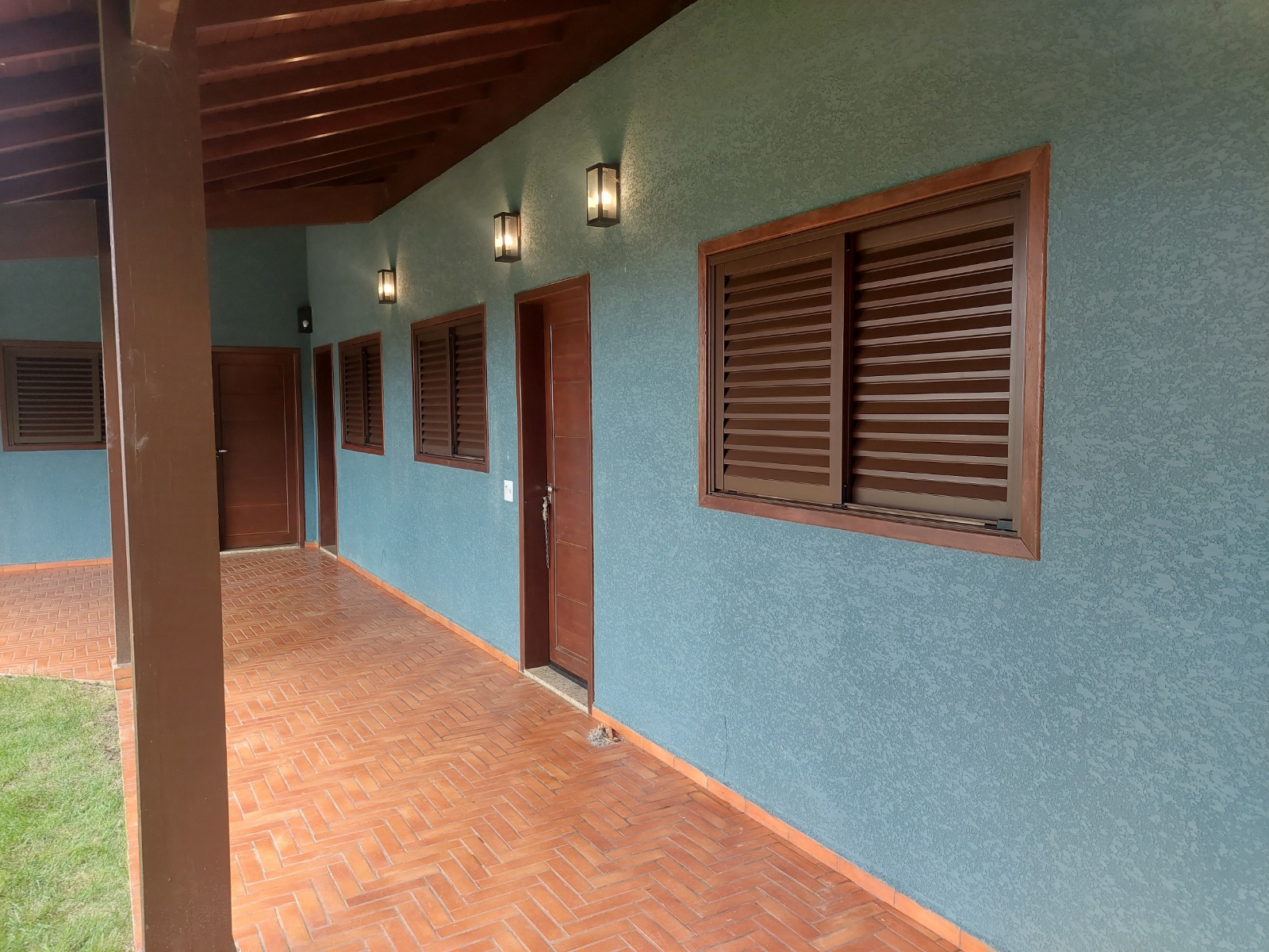 Corredor residencial com conjunto de janelas venezianas em alumínio marrom