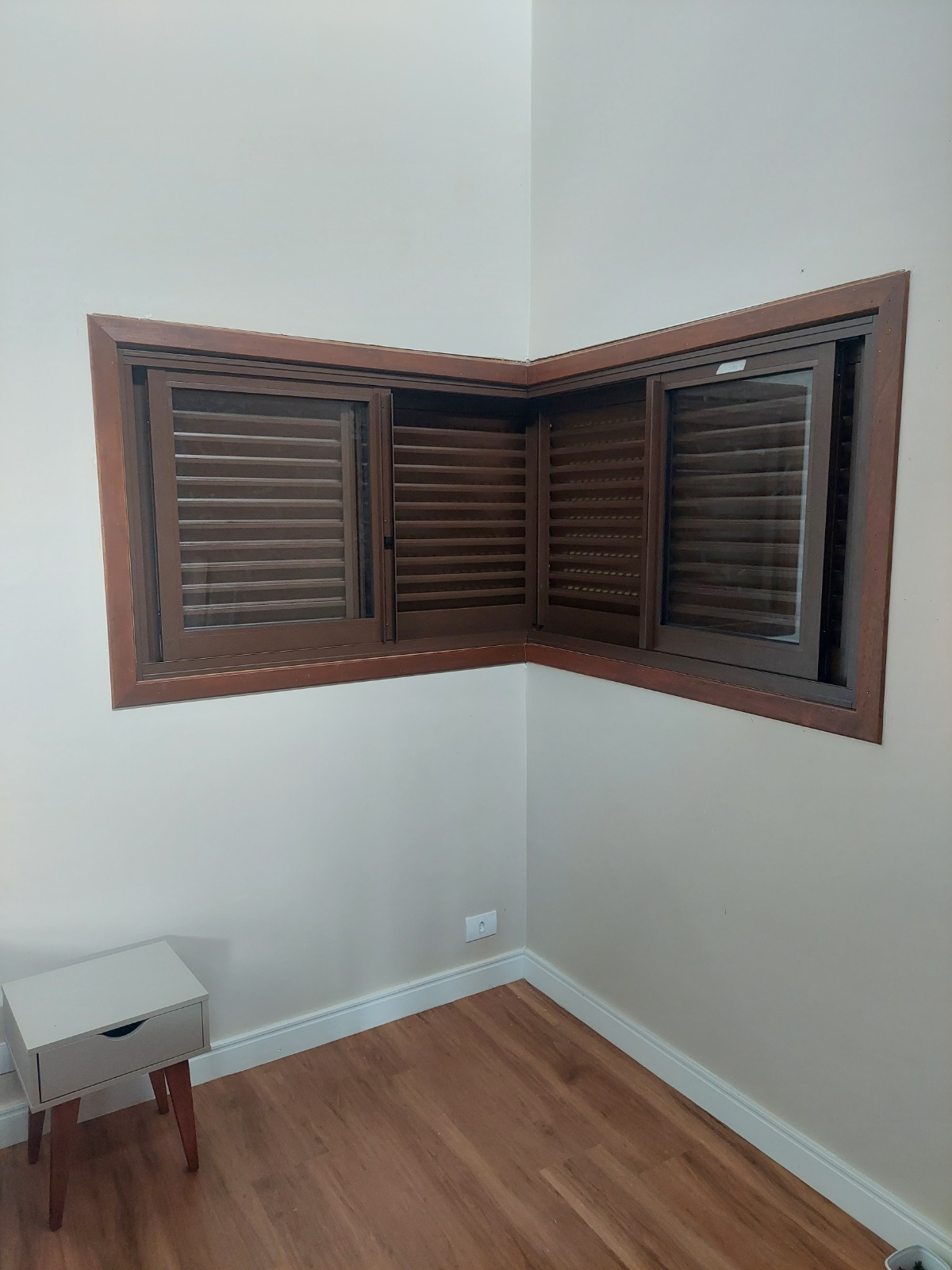 Janela de canto com vidro e venezianas vista pelo interior