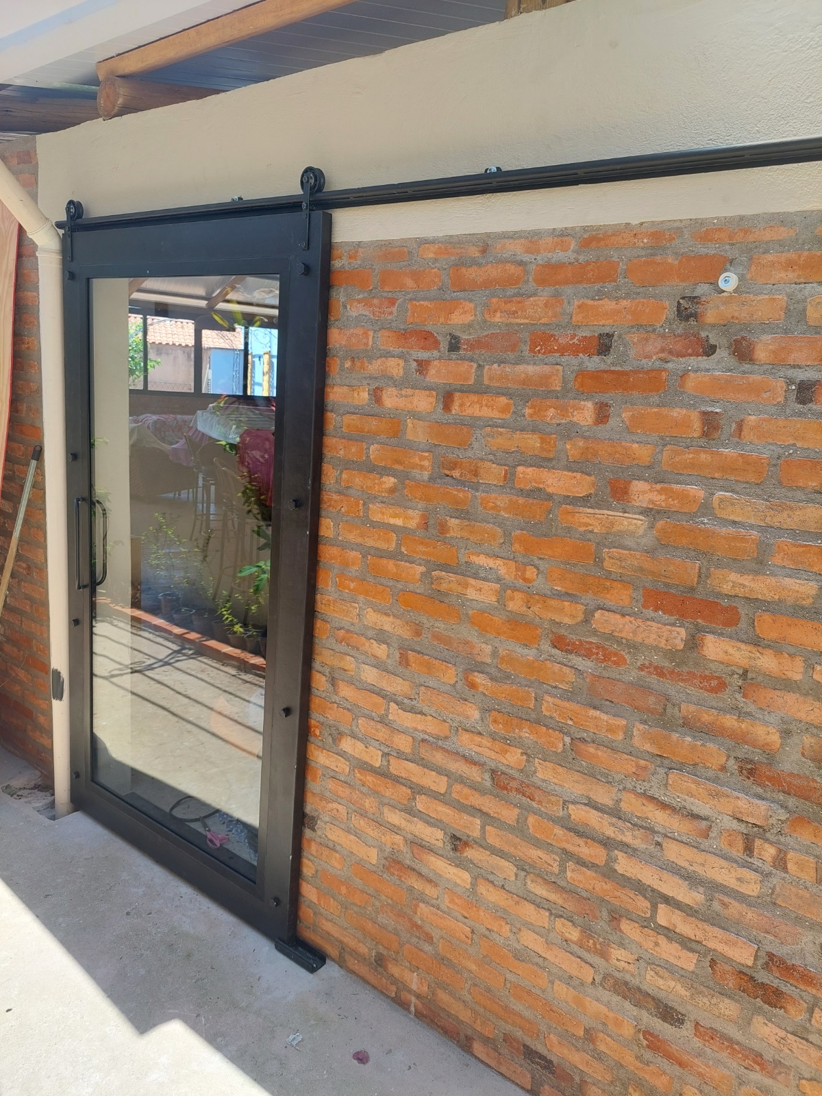 Porta de alumínio preto com vidro incolor e sistema deslizante estilo celeiro