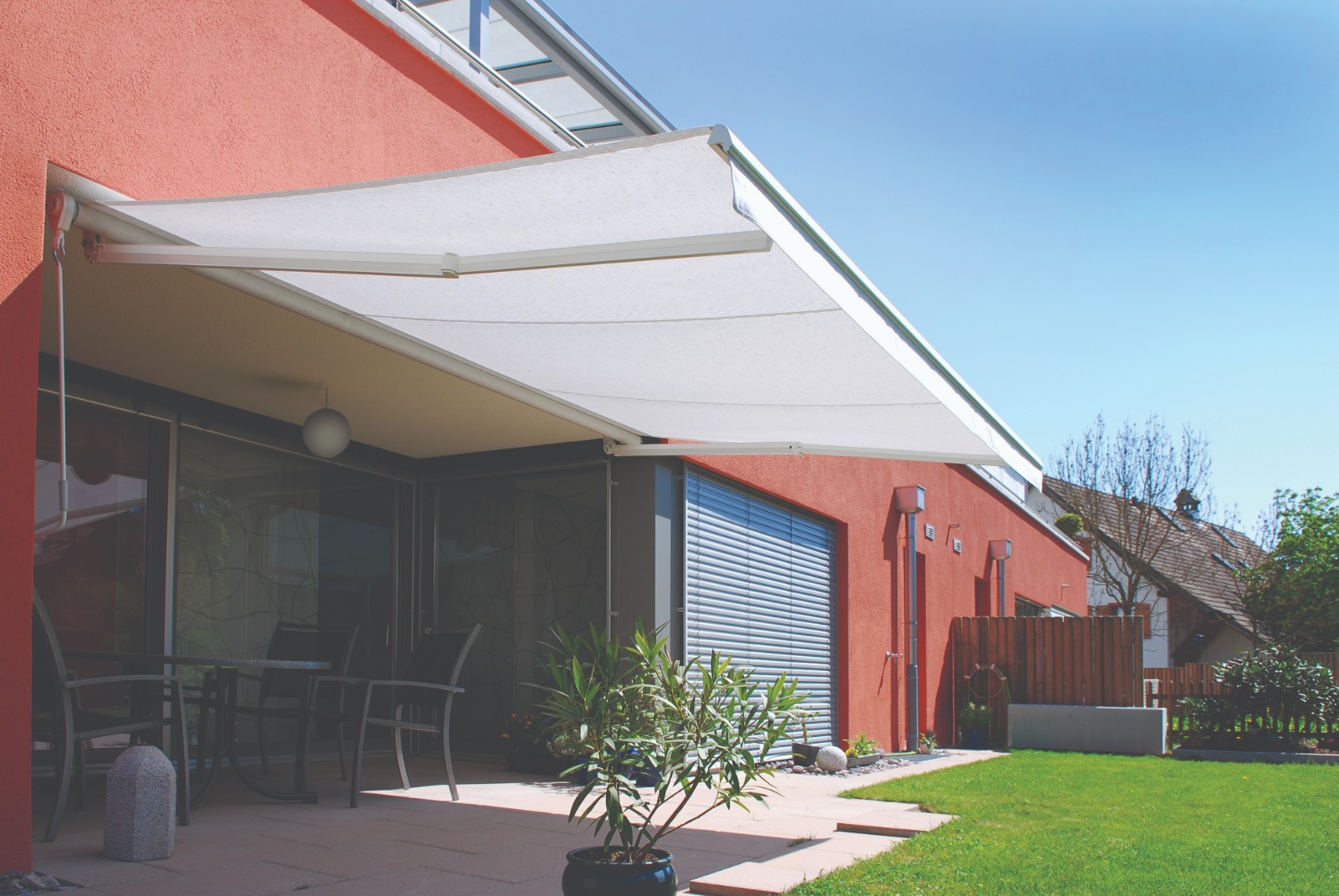 Toldo articulado claro protegendo uma varanda residencial